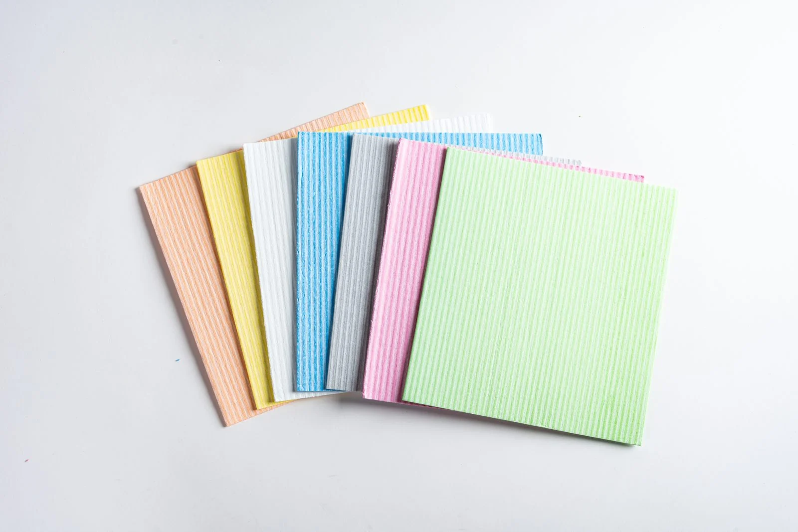 Fanned stack of assorted pastel compressed sponge sheets in green pink blue yellow and orange