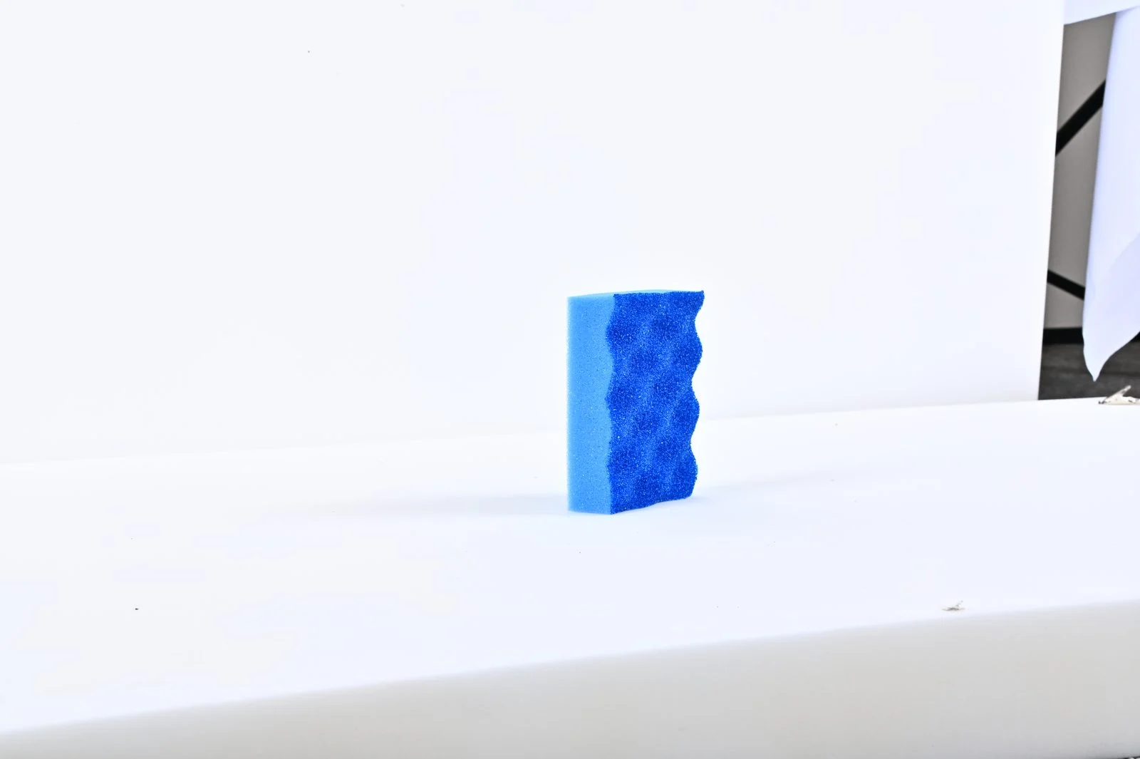 Blue wavy emery scrub sponge standing upright for removing stubborn dried wall marks